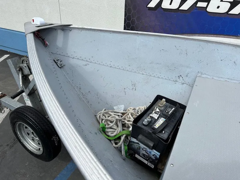 Slide: The Image of 2022 Lund WC-14 boat interior with battery and rope on trailer. - 14