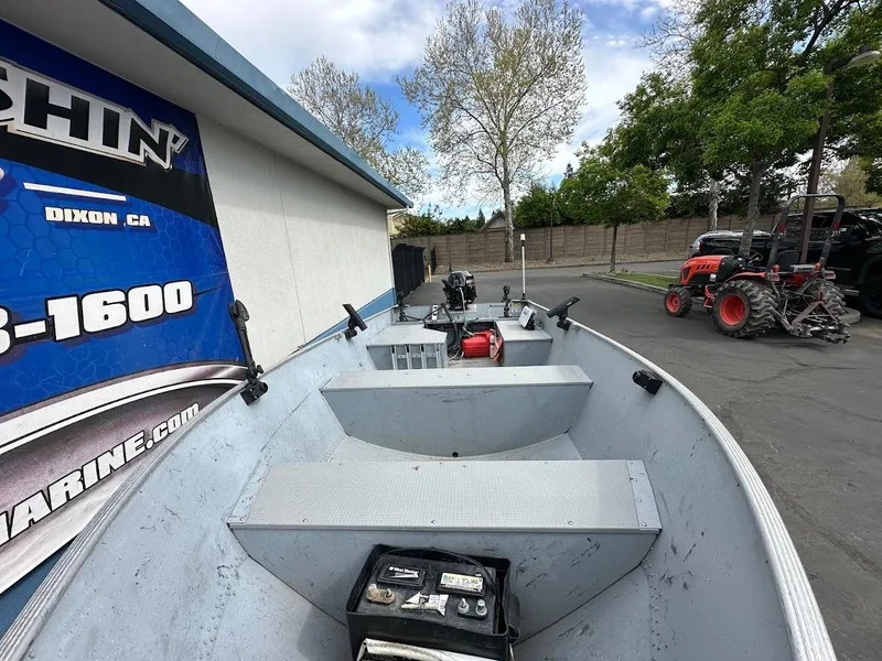 Slide: The Image of 2022 Lund WC-14 boat parked outdoors near a building and tractor. - 15