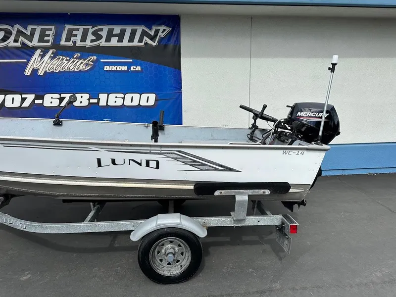 Slide: The Image of 2022 Lund WC-14 boat on trailer with Mercury outboard motor, displayed at marine dealership. - 5