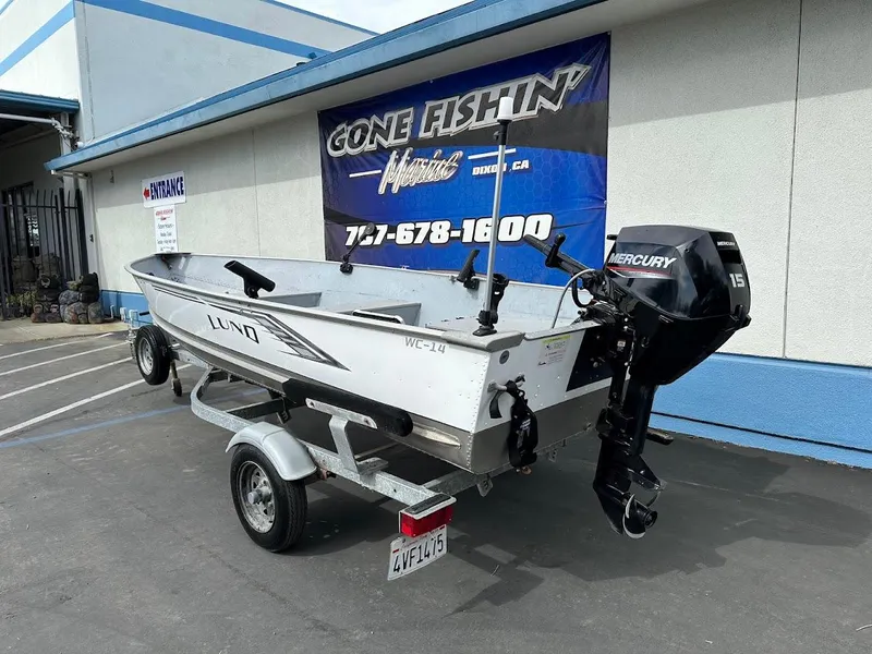 Slide: The Image of 2022 Lund WC-14 boat on trailer with Mercury outboard motor, parked outside dealership. - 6