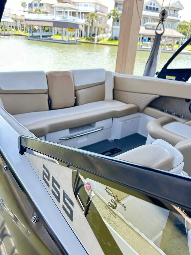 Slide: The Image of 2016 Scarab 255 H.O. Platinum boat interior with beige seating, docked by waterfront homes. - 11