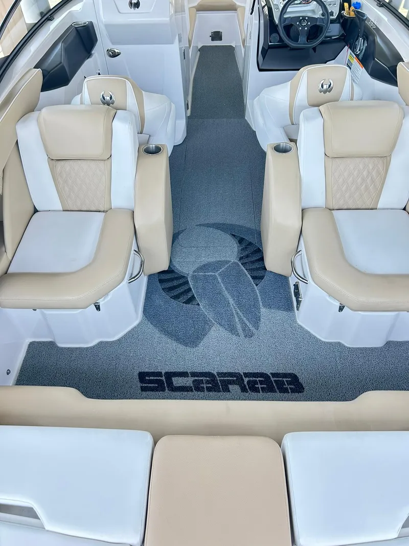 Slide: The Image of Interior of 2016 Scarab 255 H.O. Platinum boat with beige seating and logo on carpet. - 32