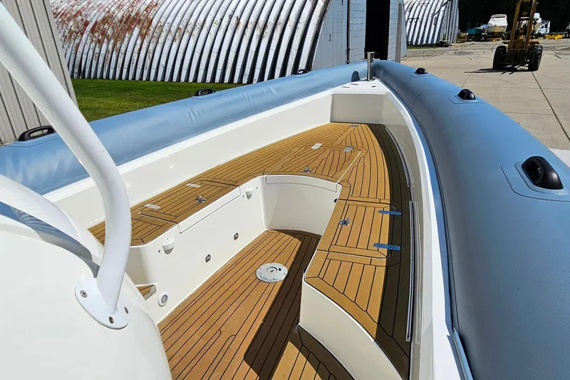 Slide: The Image of 2012 Cougar R10 Rigid Inflatable boat with wooden deck, docked near industrial buildings. - 12