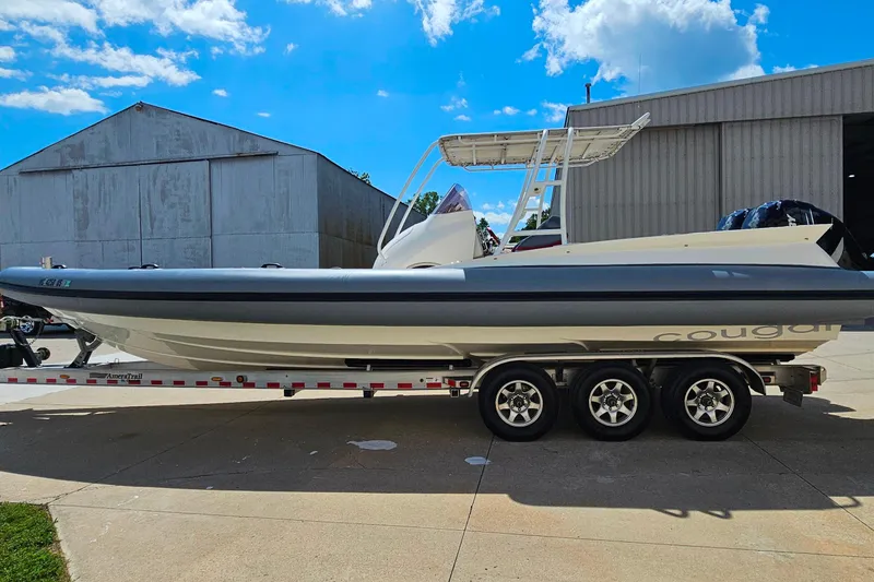 Slide: The Image of 2012 Cougar R10 Rigid Inflatable boat on trailer, parked near industrial buildings under blue sky. - 3