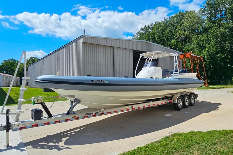 Slide: The Image of 2012 Cougar R10 Rigid Inflatable boat on trailer, parked near a large shed. - 39