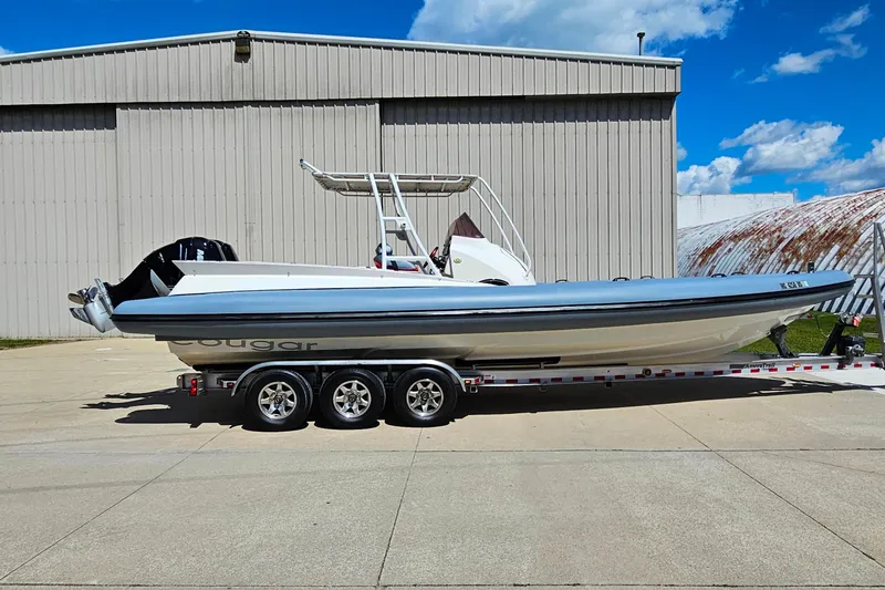 Slide: The Image of 2012 Cougar R10 Rigid Inflatable boat on trailer, parked near a large building under a blue sky. - 9