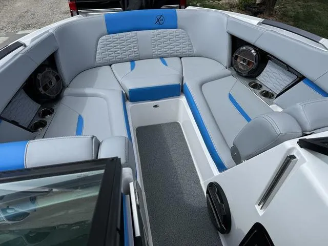 Slide: The Image of 2022 MasterCraft X24 boat interior with gray and blue seating, cup holders, and speakers. - 13