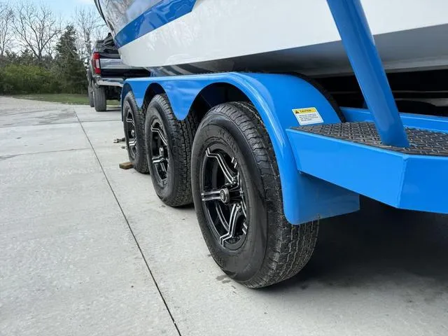 Slide: The Image of 2022 MasterCraft X24 boat on a blue triple-axle trailer, parked on concrete. - 17