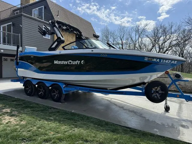 Slide: The Image of 2022 MasterCraft X24 boat on trailer, parked near modern house, sunny day. - 5