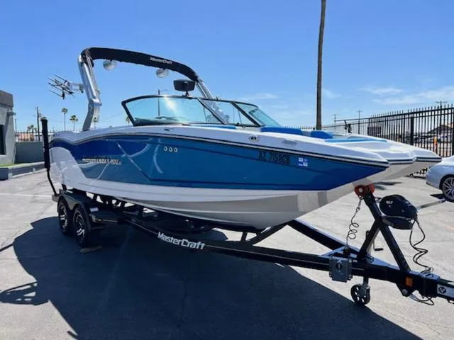 Slide: The Image of 2018 MasterCraft NXT22 boat on trailer, blue and white design, parked outdoors. - 4
