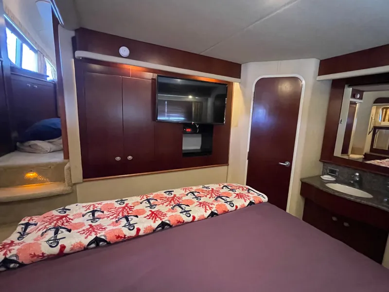 Slide: The Image of Luxurious 2005 Sea Ray motor yacht bedroom with TV, wood cabinetry, and nautical-themed bedding. - 27