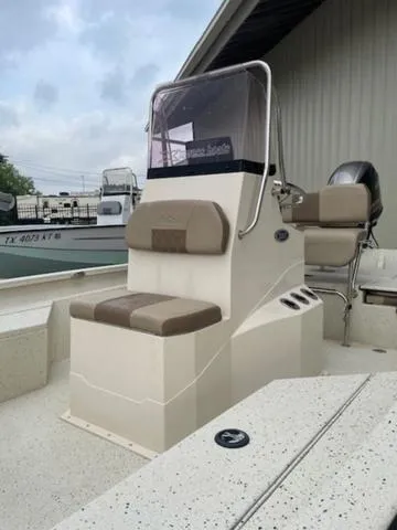 Slide: The Image of 2019 Xpress SW20B boat with beige seating and console, docked near a building. - 5
