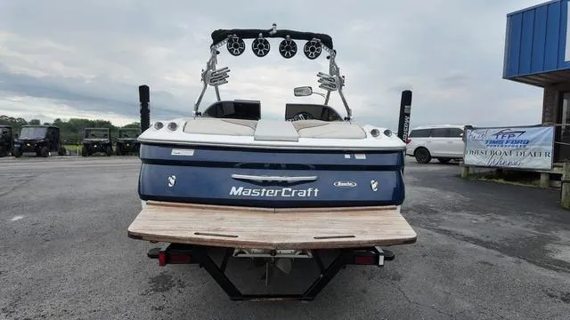 Slide: The Image of 2011 MasterCraft X45 boat, rear view, parked outdoors with a cloudy sky backdrop. - 4