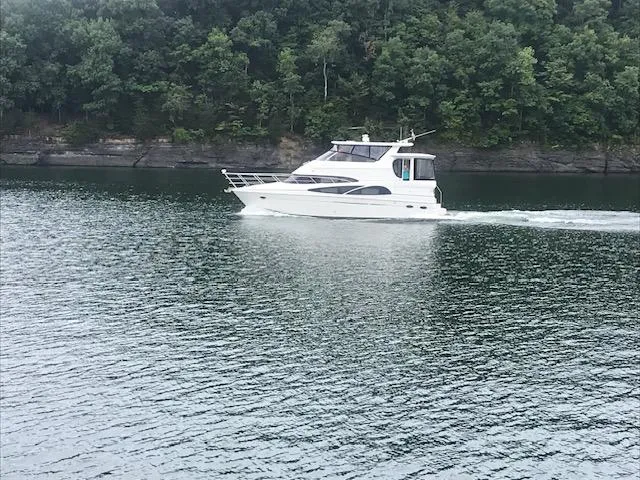 Slide: The Image of 2005 Carver 46 Motor Yacht cruising on a serene lake with forested shoreline. - 46