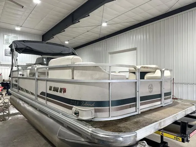 Slide: The Image of Pontoon boat in a garage, Premier 2023 Island Leisure model, white and gray design. - 3