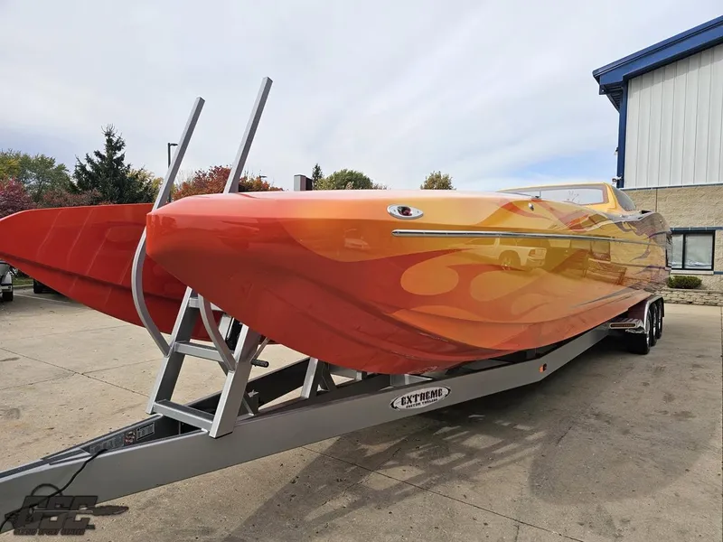 Slide: The Image of 2008 Eliminator 36 Daytona Coupe boat with vibrant orange and yellow design on trailer. - 34