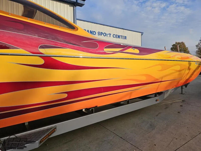 Slide: The Image of 2008 Eliminator 36 Daytona Coupe with vibrant flame design parked outside a sports center. - 5