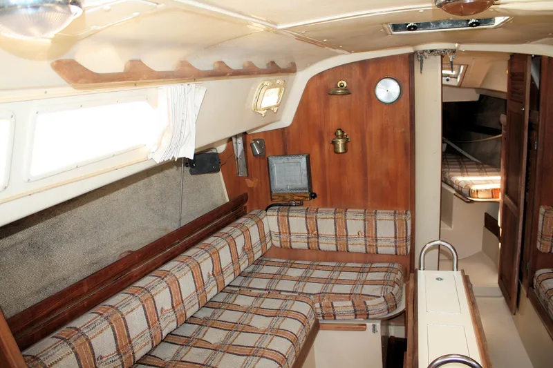 Slide: The Image of 1981 O'Day 34 sailboat interior with plaid seating, wood paneling, and cozy cabin layout. - 17