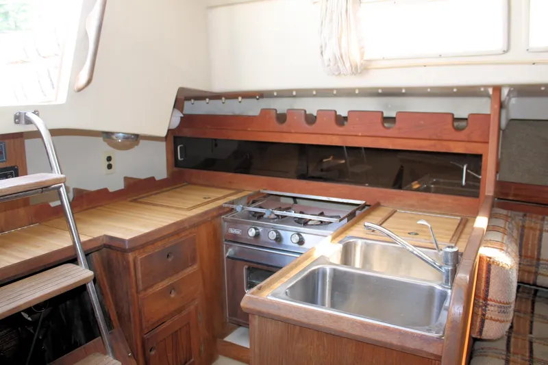 Slide: The Image of 1981 O'Day 34 yacht kitchen with wooden cabinetry, stove, and sink. - 23