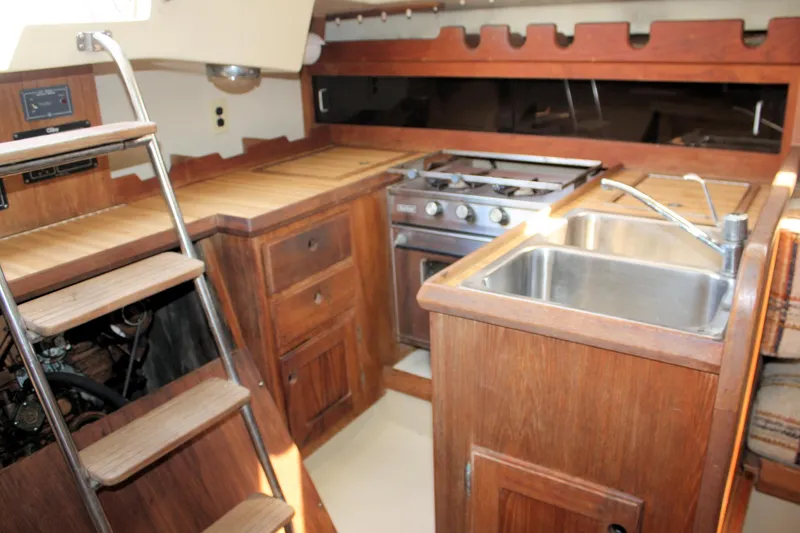 Slide: The Image of 1981 O'Day 34 yacht interior with wooden cabinetry, stove, and sink in the galley area. - 24