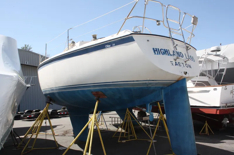 Slide: The Image of 1981 O'Day 34 sailboat on stands, named "Highland Lass," in a boatyard. - 3