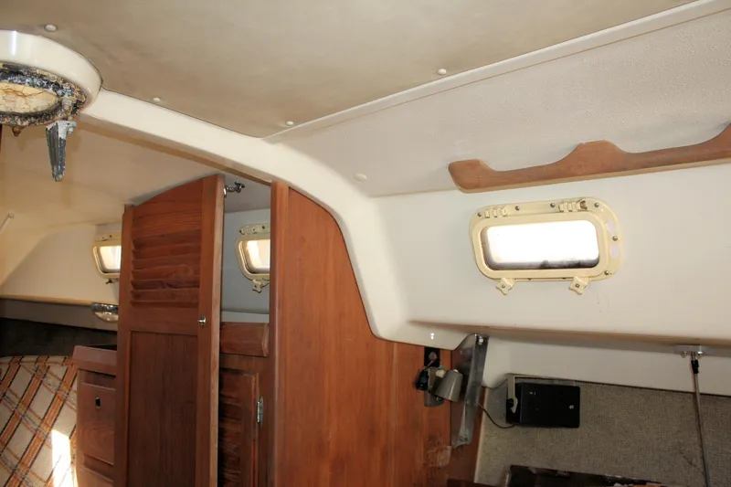 Slide: The Image of Interior of a 1981 O'Day 34 sailboat, featuring wooden cabinetry and portholes. - 39
