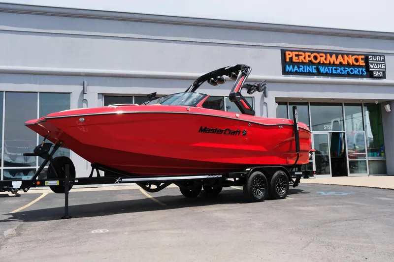 Slide: The Image of 2025 MasterCraft X24 boat in vibrant red outside Performance Marine Watersports store. - 1