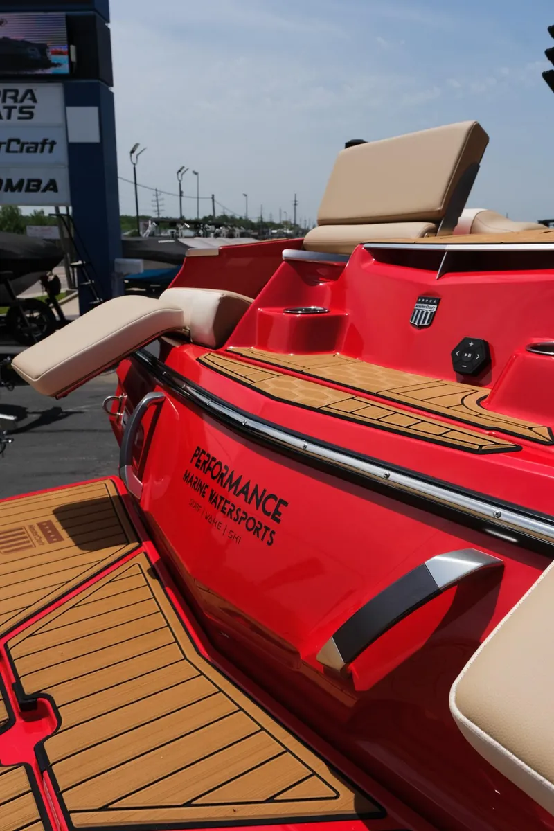 Slide: The Image of 2025 MasterCraft X24 boat with red exterior and tan seating, showcased at a marina. - 12