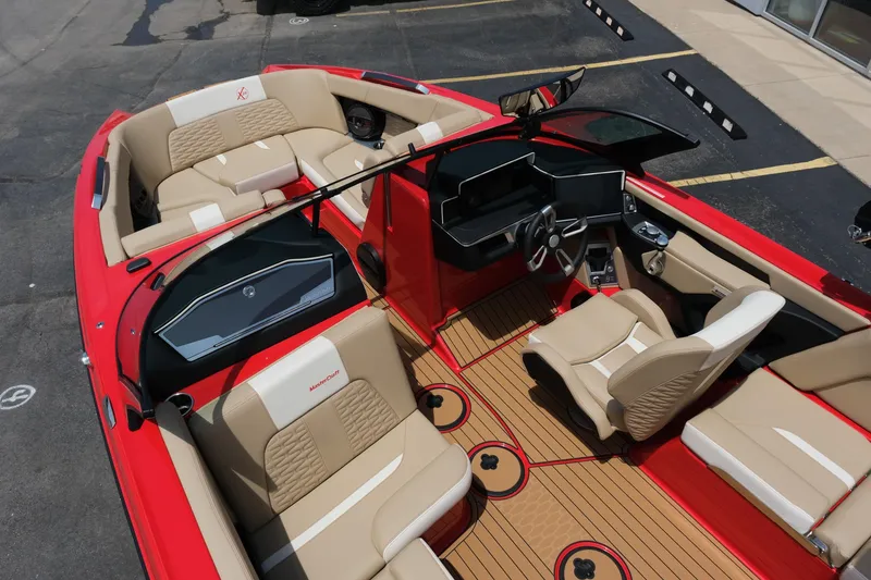 Slide: The Image of 2025 MasterCraft X24 boat interior with red and beige seating, modern dashboard, and wood-style flooring. - 19