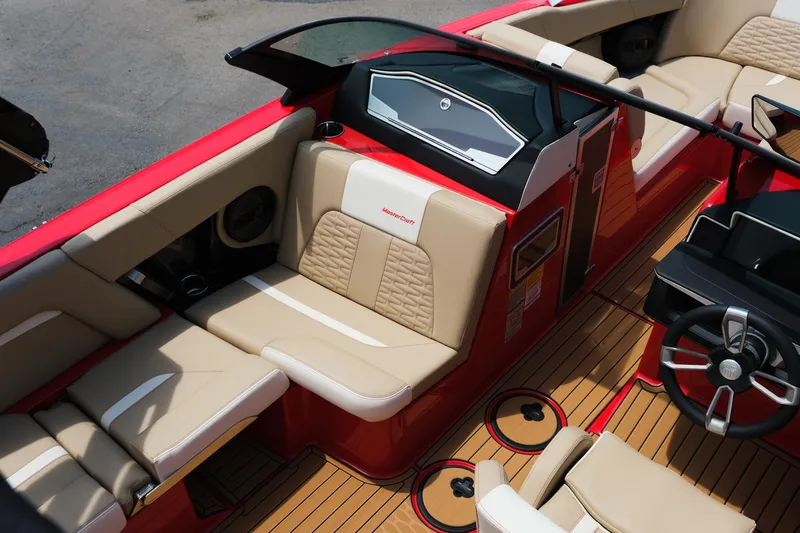 Slide: The Image of 2025 MasterCraft X24 boat interior with beige seating and red accents. - 22