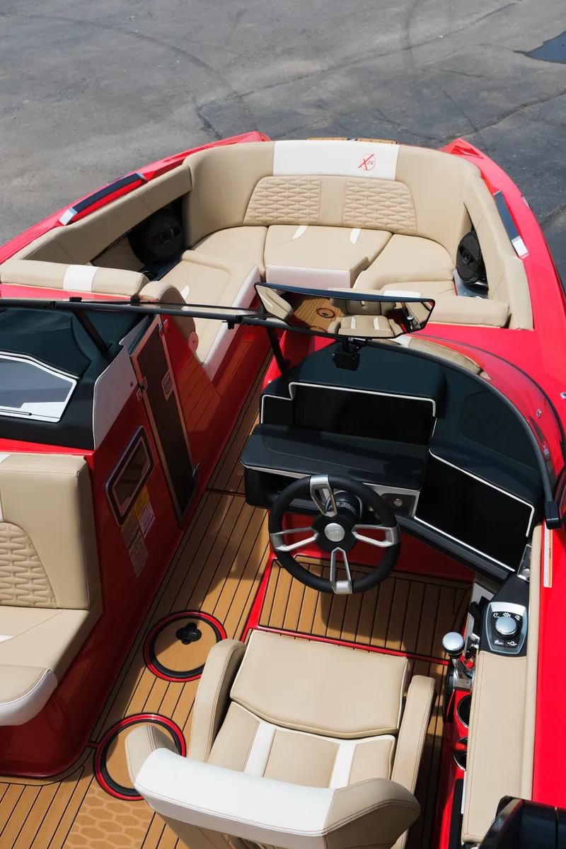 Slide: The Image of 2025 MasterCraft X24 boat interior with red and beige seating, modern dashboard, and wooden flooring. - 23