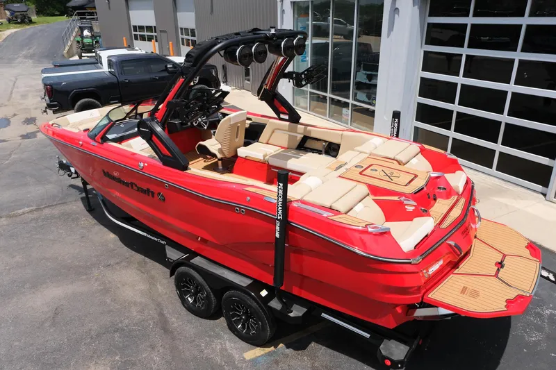 Slide: The Image of 2025 MasterCraft X24 boat in vibrant red, parked on a trailer outside a garage. - 4