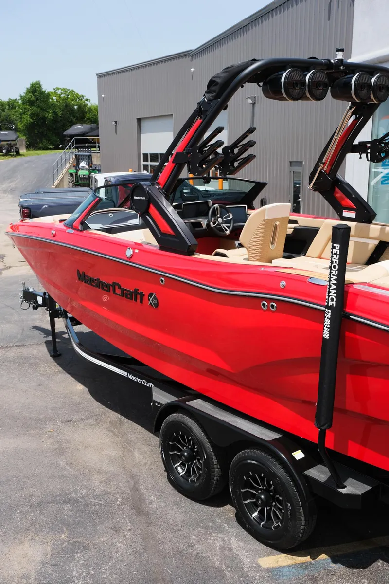 Slide: The Image of 2025 MasterCraft X24 boat in vibrant red on a trailer, parked outdoors. - 5