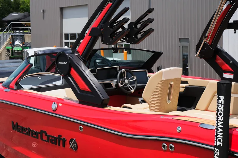 Slide: The Image of 2025 MasterCraft X24 boat with red exterior and beige interior, docked near a building. - 7