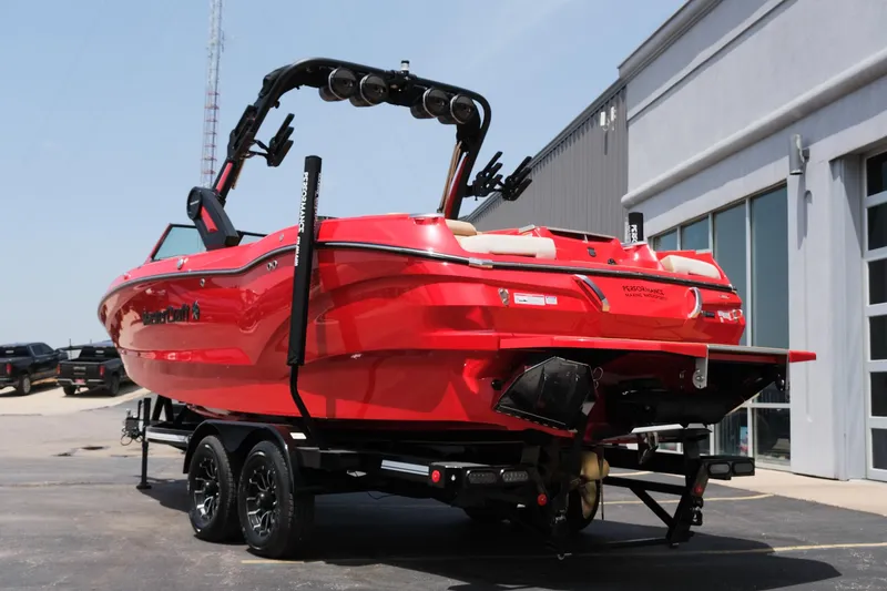 Slide: The Image of 2025 MasterCraft X24 boat in vibrant red on a trailer, parked outside a building. - 8