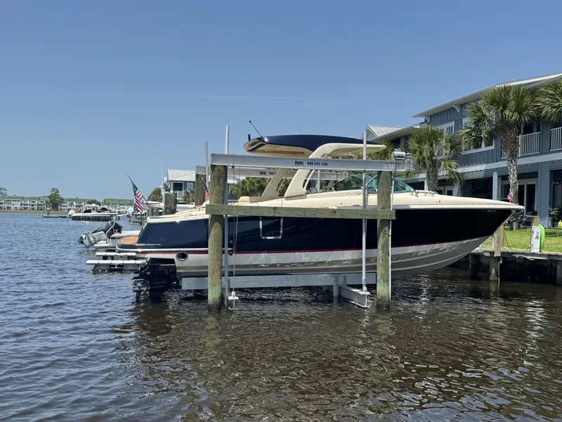 Slide: The Image of 2020 Chris-Craft Launch 31 GT cruising on water near a bridge under a cloudy sky. - 11