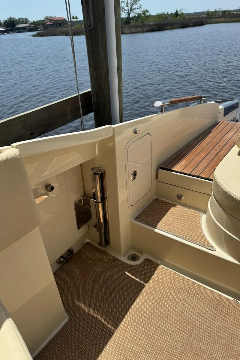 Slide: The Image of 2020 Chris-Craft Launch 31 GT boat interior, featuring elegant wood and beige upholstery by the water. - 84
