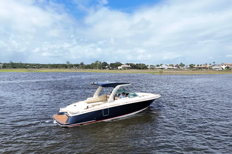 Slide: The Image of 2020 Chris-Craft Launch 31 GT boat cruising on a scenic lake under a partly cloudy sky. - 96