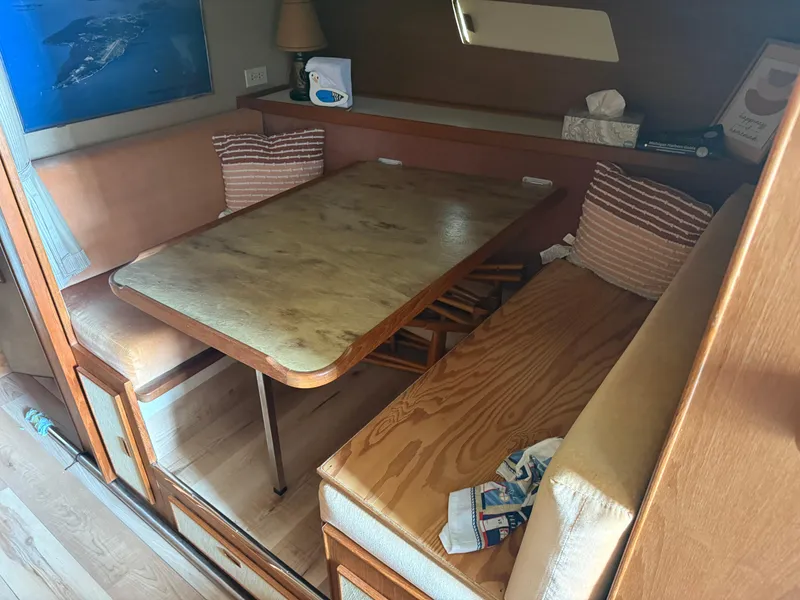 Slide: The Image of 1985 Trojan F36 interior with wooden table, cushioned seating, and nautical decor. - 12