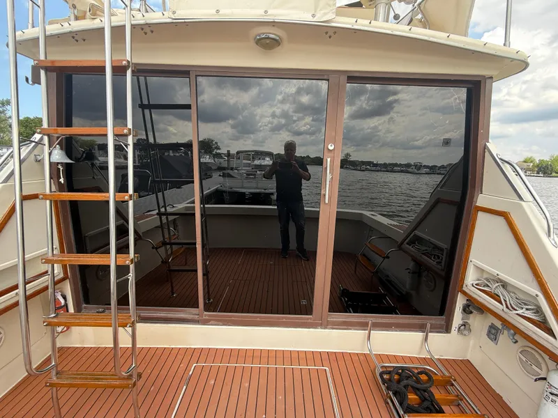 Slide: The Image of 1985 Trojan F36 boat with wooden deck and glass doors, docked by a lake. - 27