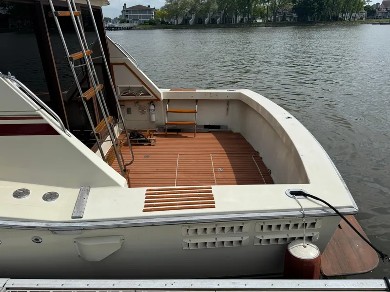 Slide: The Image of 1985 Trojan F36 boat with wooden deck, docked by a calm river. - 3