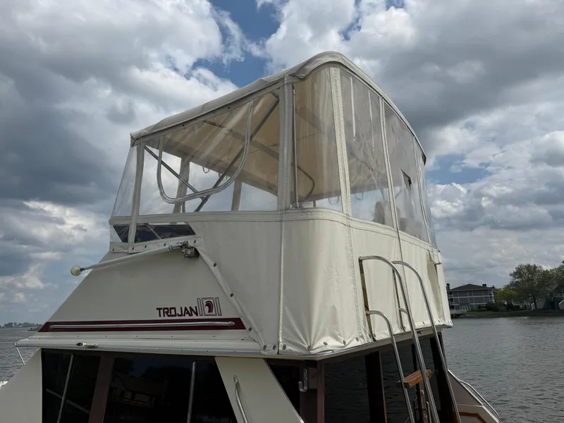 Slide: The Image of 1985 Trojan F36 boat with enclosed flybridge, docked under cloudy skies. - 30
