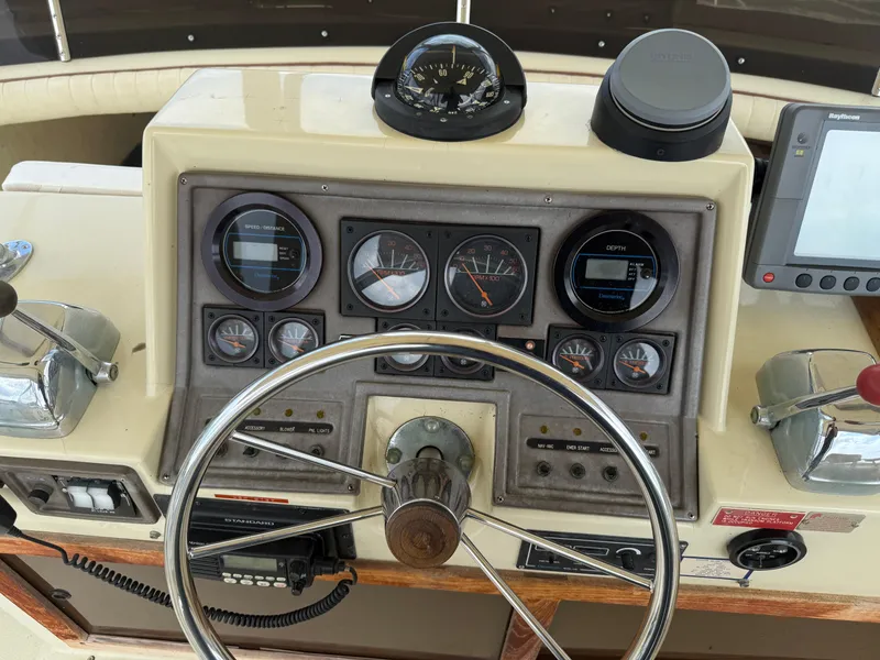 Slide: The Image of 1985 Trojan F36 boat dashboard with steering wheel, gauges, and navigation equipment. - 32