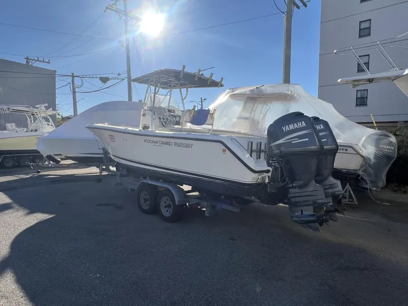 Slide: The Image of 2005 Pursuit 2570 Center Console boat with Yamaha engines on a trailer in a sunny marina. - 27
