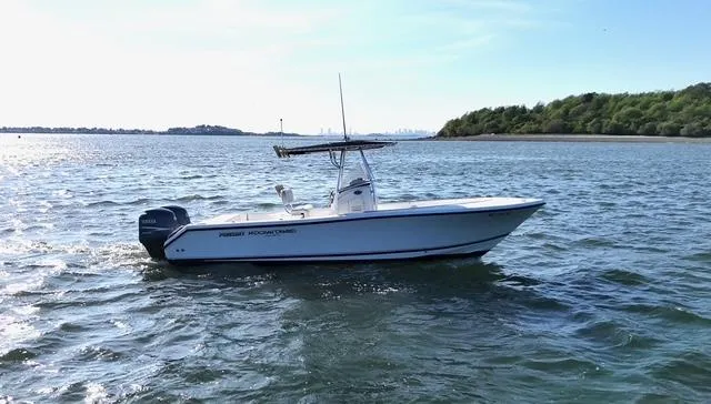 Slide: The Image of 2005 Pursuit 2570 Center Console boat cruising on a calm sea near a wooded shoreline. - 4