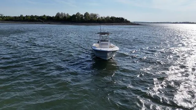 Slide: The Image of 2005 Pursuit 2570 Center Console boat on open water, near a wooded shoreline. - 5