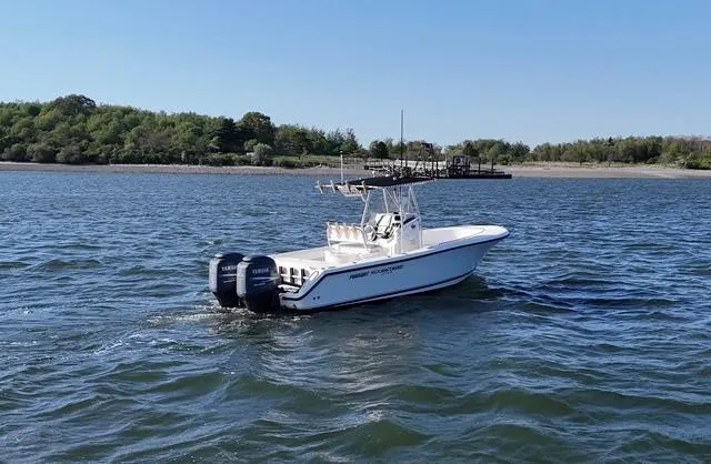 Slide: The Image of 2005 Pursuit 2570 Center Console boat on water, dual engines, scenic shoreline background. - 6