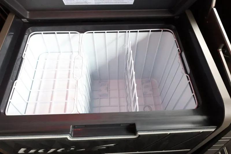 Slide: The Image of Open storage compartment in 2025 Tigé Ultré 25ZX boat, featuring wire dividers. - 44