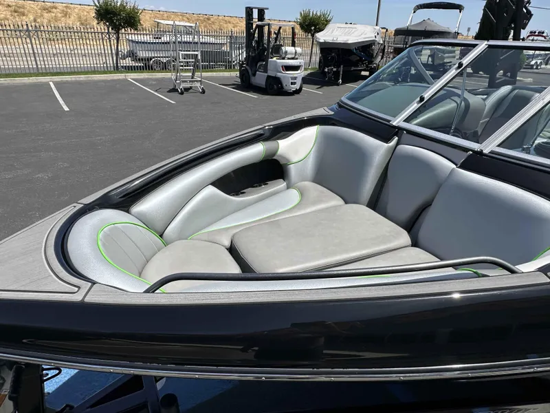 Slide: The Image of 2024 Sanger V215 S boat interior with gray and green seating in a parking lot. - 12