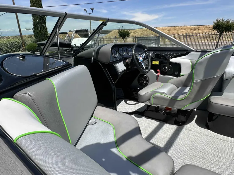 Slide: The Image of 2024 Sanger V215 S boat interior with gray and green-trimmed seats, steering wheel, and dashboard. - 13